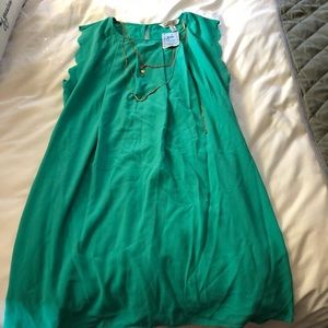 Teal scalloped arm dress with gold necklace.